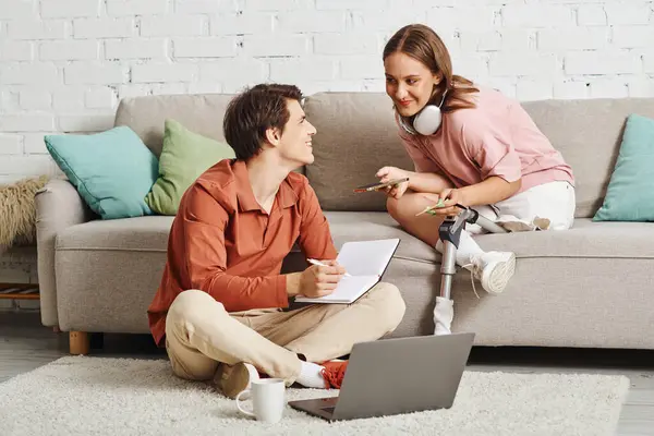 A woman with a prosthetic leg and her boyfriend working together at home. — Stock Photo