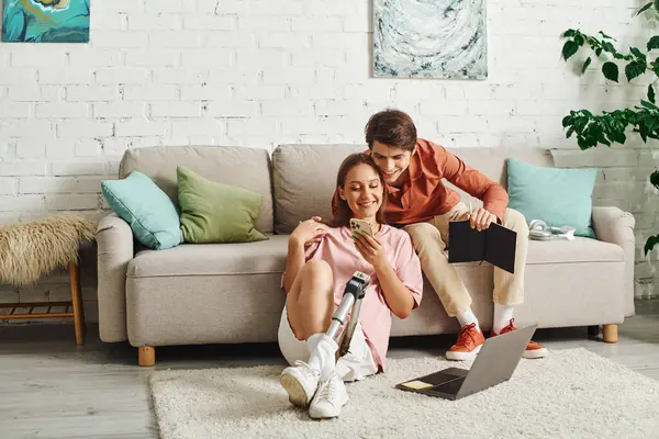 A woman with a prosthetic leg and her boyfriend relax on the floor of their living room. — Stock Photo