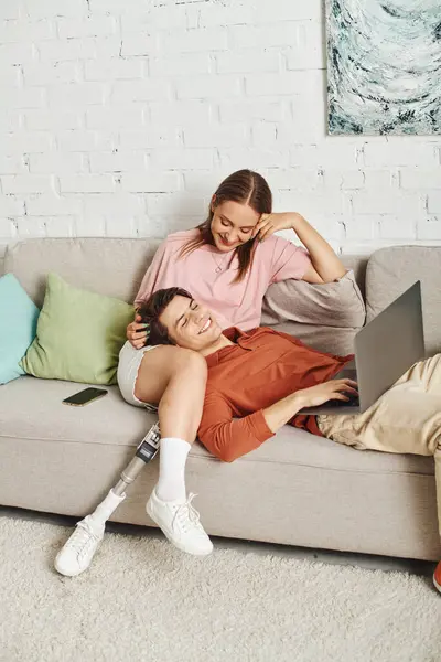 A woman with a prosthetic leg relaxes with her boyfriend on a couch. — Stock Photo
