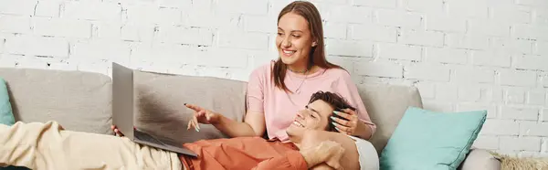 A woman with a prosthetic leg cuddles with her boyfriend on a couch while looking at a laptop. — Stock Photo