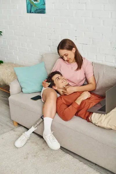 A woman with a prosthetic leg relaxes with her boyfriend on a couch. — Stock Photo