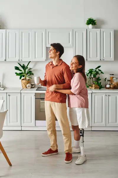 A couple stands in their kitchen, smiling and enjoying a cup of coffee. — Stock Photo