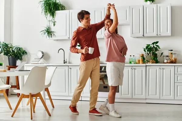 A couple, with the woman having a prosthetic leg, dance playfully in their kitchen. — Stock Photo