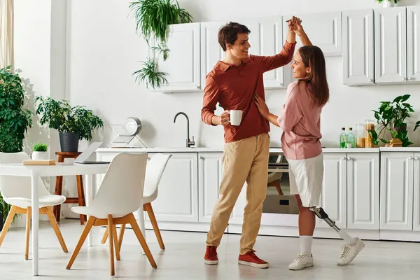 A couple dances in their kitchen, the woman with a prosthetic leg. — Stock Photo