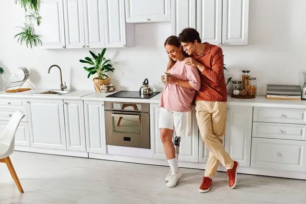 A woman with a prosthetic leg leans against her boyfriend in a modern kitchen. — Stock Photo