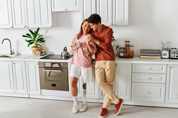 A woman with a prosthetic leg enjoys a coffee with her boyfriend in their kitchen. — Stock Photo