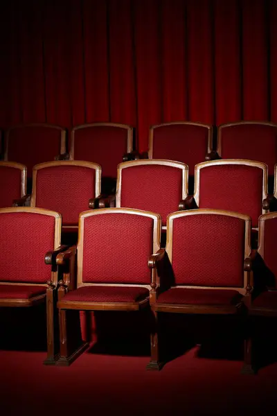 Assentos vermelhos vazios do teatro sob uma cortina vermelha. — Fotografia de Stock