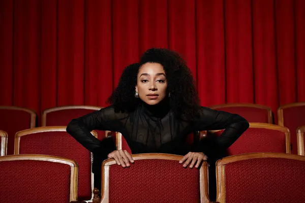 Une femme afro-américaine à la mode regarde un film, captivée par l'histoire qui se déroule à l'écran. — Photo de stock