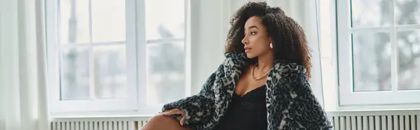 A stylish African American woman wearing a trendy outfit poses against a window in a studio setting. — Stock Photo