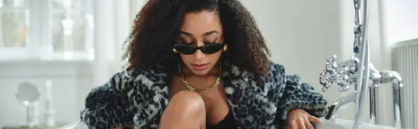 A fashionable African American woman in a trendy outfit poses while sitting in a studio setting. — Stock Photo