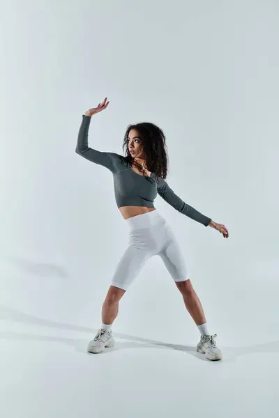 A young African American woman in workout clothes poses against a white backdrop, showcasing her athleticism and fitness. — Stock Photo