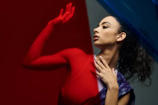 Una giovane donna con lunghi capelli ricci posa davanti a uno sfondo rosso e blu. — Foto stock