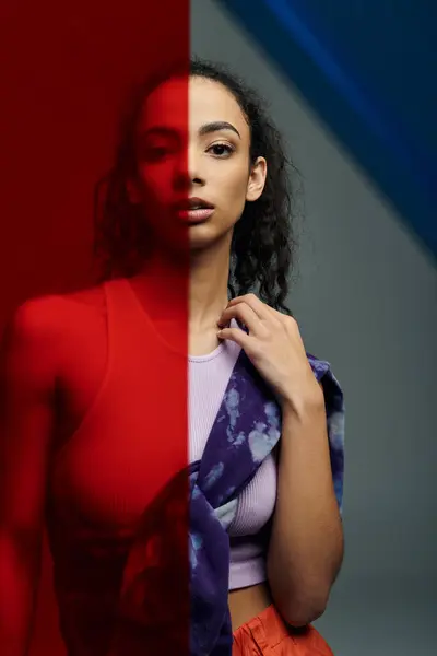 A young woman in athletic wear stands with a red pane of glass behind her, while a blue pane is reflected in the background. — Stock Photo