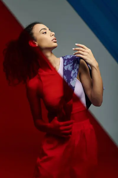 A young woman, posing with colorful glass panels behind her in a studio. — Stock Photo