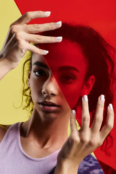 A young woman poses in a studio, holding a red panel in front of her face — Stock Photo