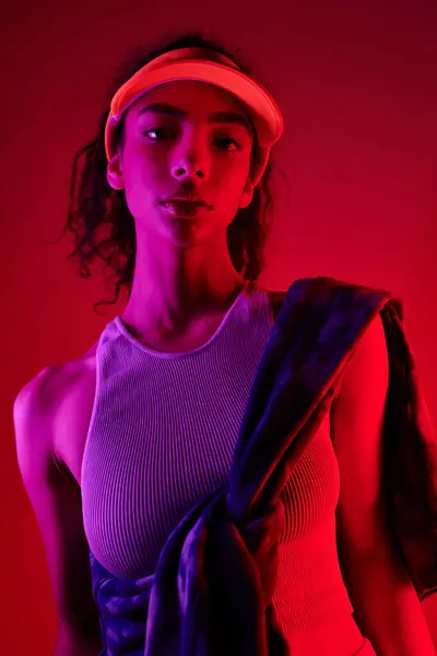 A young woman with dark curly hair poses confidently in a studio setting, bathed in neon light. — Stock Photo