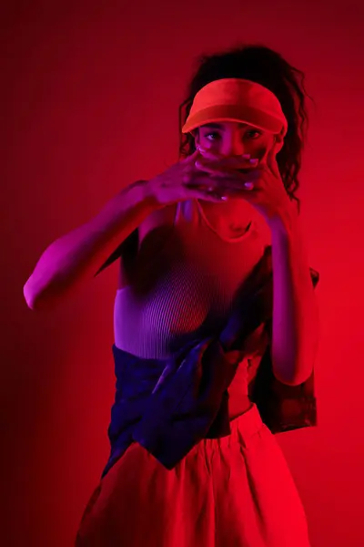 Eine junge Frau posiert in einem Studio, das in leuchtendes Neonlicht getaucht ist und ihren Stil mit Sport und Mode verbindet. — Stockfoto
