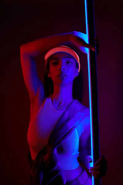 A young African American woman poses in a studio lit by neon lights, showcasing a sporty and fashionable look. — Stock Photo