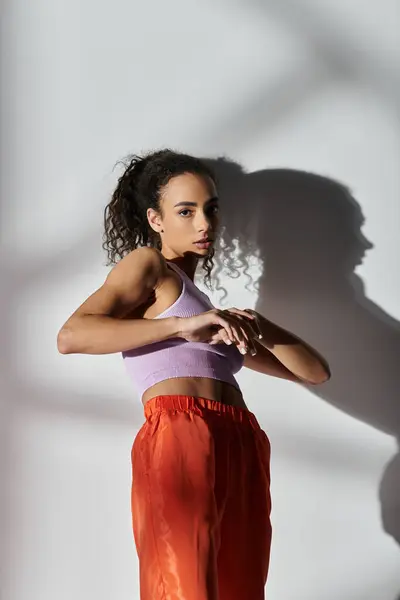 A young woman in a trendy outfit poses against a white backdrop. — Stock Photo