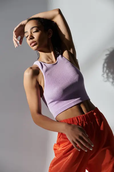 Una giovane donna in abiti alla moda posa in uno studio con uno sfondo grigio. — Foto stock