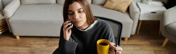 A woman sits on a chair in her home, working and talking on the phone. — Stock Photo