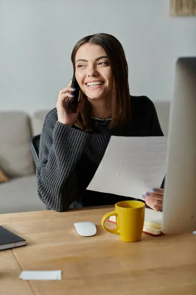 A smiling young woman talking on the phone, and holding a document. — Stock Photo