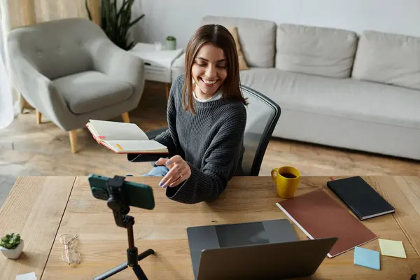 Una joven sonríe mientras filma un video en su escritorio de la oficina en casa. — Stock Photo