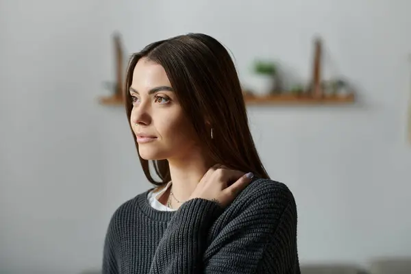 A young woman sits at home, lost in thought — Stock Photo