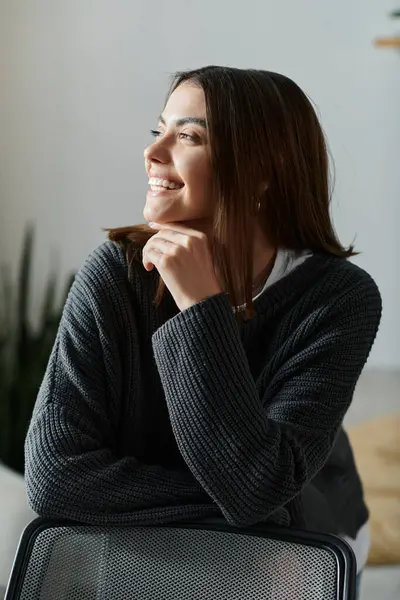 A young woman in a grey sweater sits thoughtfully in a home office, lost in creative thought while working on a digital marketing project. — Stock Photo