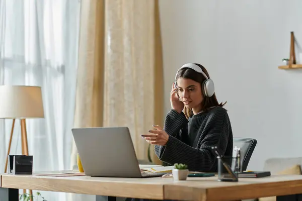 A young woman works on her laptop at a desk in her home office. — Stock Photo