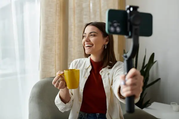 Eine junge Frau filmt einen Vlog, während sie einen Smartphone-Stabilisator in der Hand hält und Kaffee nippt. — Stockfoto