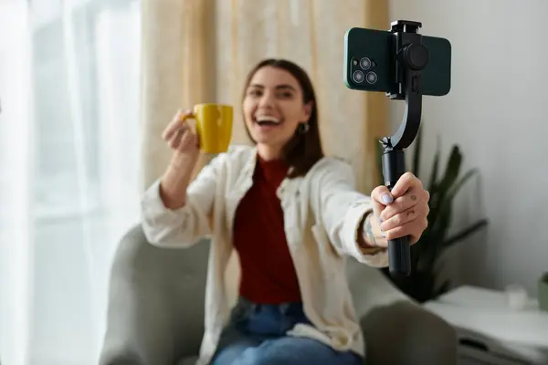 A young woman, dressed casually, vlogs while holding a smartphone stabilizer, creating video content. — Stock Photo