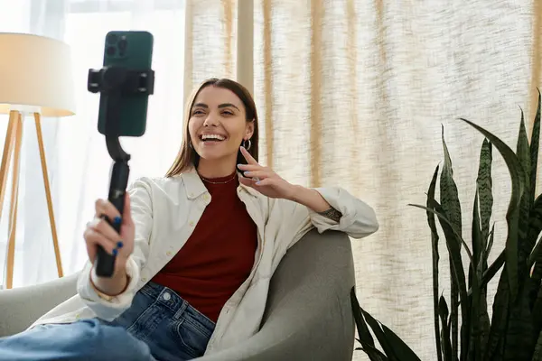A young woman, in casual attire, records a video, smiling brightly as she uses a phone stabilizer. — Stock Photo