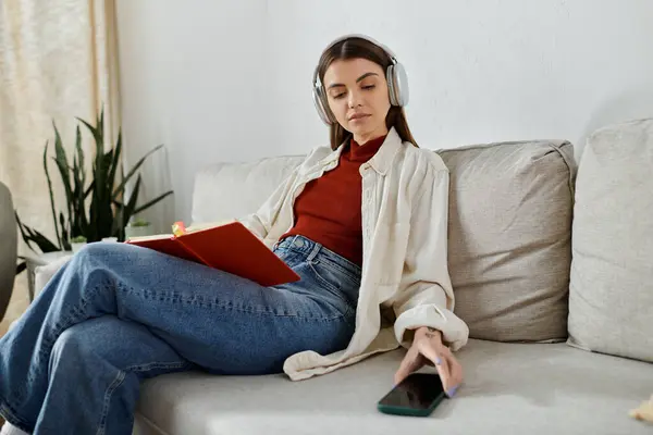A young woman wearing headphones is relaxing on a couch, listening to music. — Stock Photo