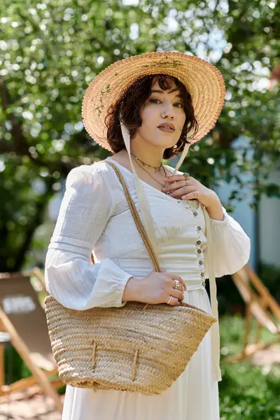A young woman in a straw hat and white dress smiles in a sunny garden. — Stock Photo
