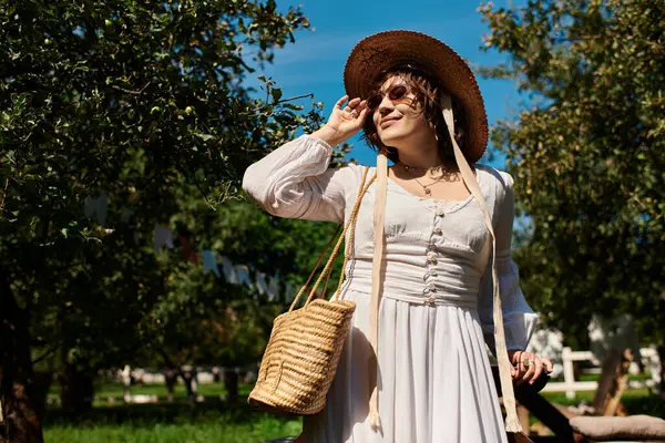 A young woman in a white dress and straw hat smiles in a summer garden. — Stock Photo