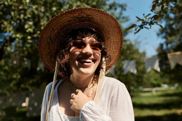 Une jeune femme dans un chapeau de paille sourit tout en profitant d'une journée ensoleillée dans un jardin d'été. — Photo de stock