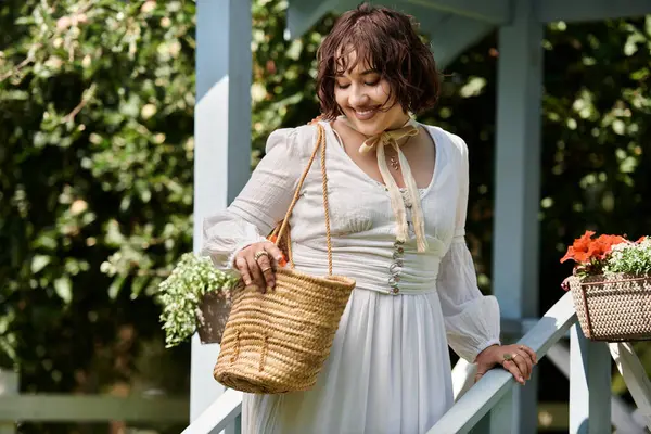 A young woman in a white blouse and straw hat walks through a summer garden, holding a woven basket. — Stock Photo