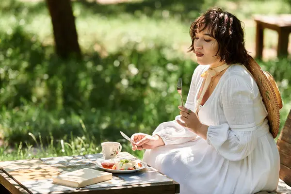 Eine brünette Frau im weißen Kleid genießt einen gemütlichen Brunch in einem üppigen Sommergarten. — Stockfoto