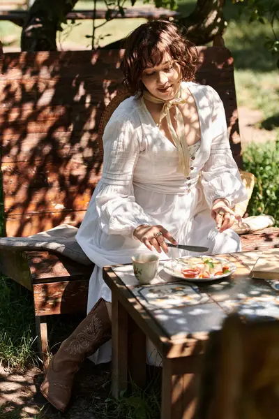 Uma mulher morena em um vestido branco desfruta de um brunch de verão ao ar livre em um cenário de jardim. — Fotografia de Stock