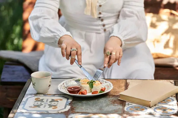 Uma jovem mulher em um vestido branco gosta de brunch ao ar livre em um jardim de verão. — Fotografia de Stock