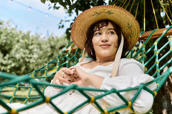 A woman relaxes in a hammock on a sunny summer day, enjoying the peace and quiet of her garden. — Stock Photo