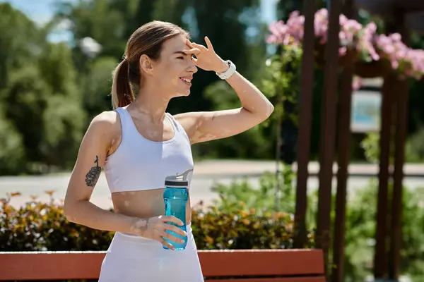 Eine junge Frau in aktiver Kleidung macht während eines sonnigen Nachmittagstrainings im Park eine Pause. — Stockfoto