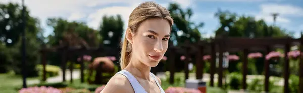 A young woman with vitiligo, wearing active wear, stands confidently in a park, her gaze fixed on the camera. — Stock Photo