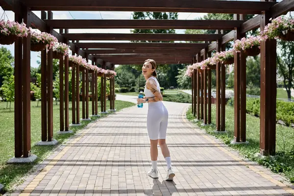 A young woman with vitiligo walks through a park, enjoying a sunny workout. — Stock Photo