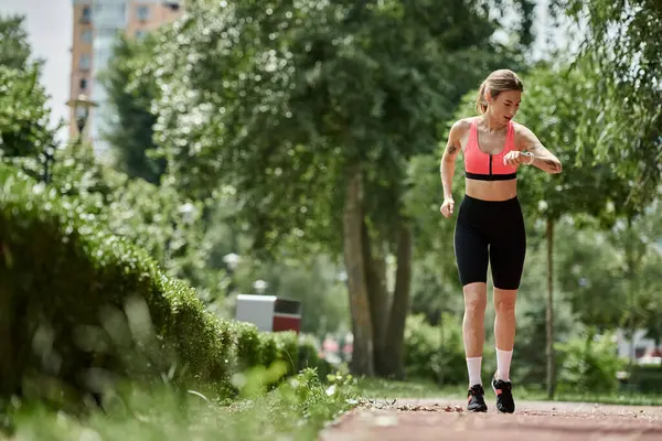 A young woman with vitiligo and a tattoo runs through a park, checking her watch. — Stock Photo