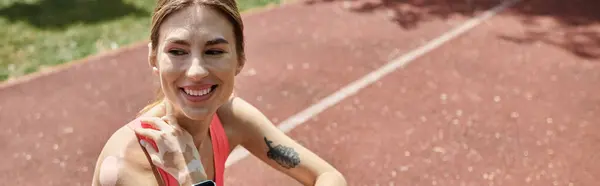 Una giovane donna con la vitiligine sorride mentre indossa un crop top rosa durante un allenamento all'aperto. — Foto stock