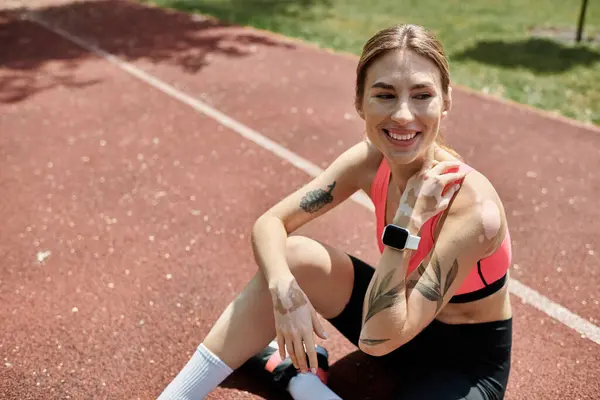 Una giovane donna con la vitiligine sorride seduta su una pista rossa in un parco. — Foto stock