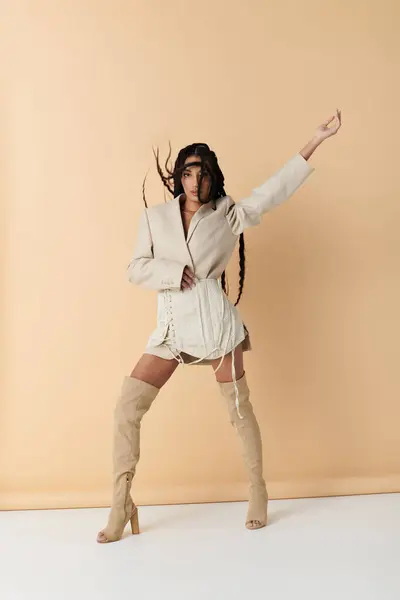 Una joven con estilo en ropa beige posa sobre un fondo neutro. - foto de stock