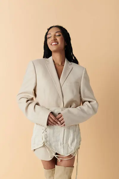 Una joven con una chaqueta blanca y falda posa sobre un fondo beige. — Stock Photo